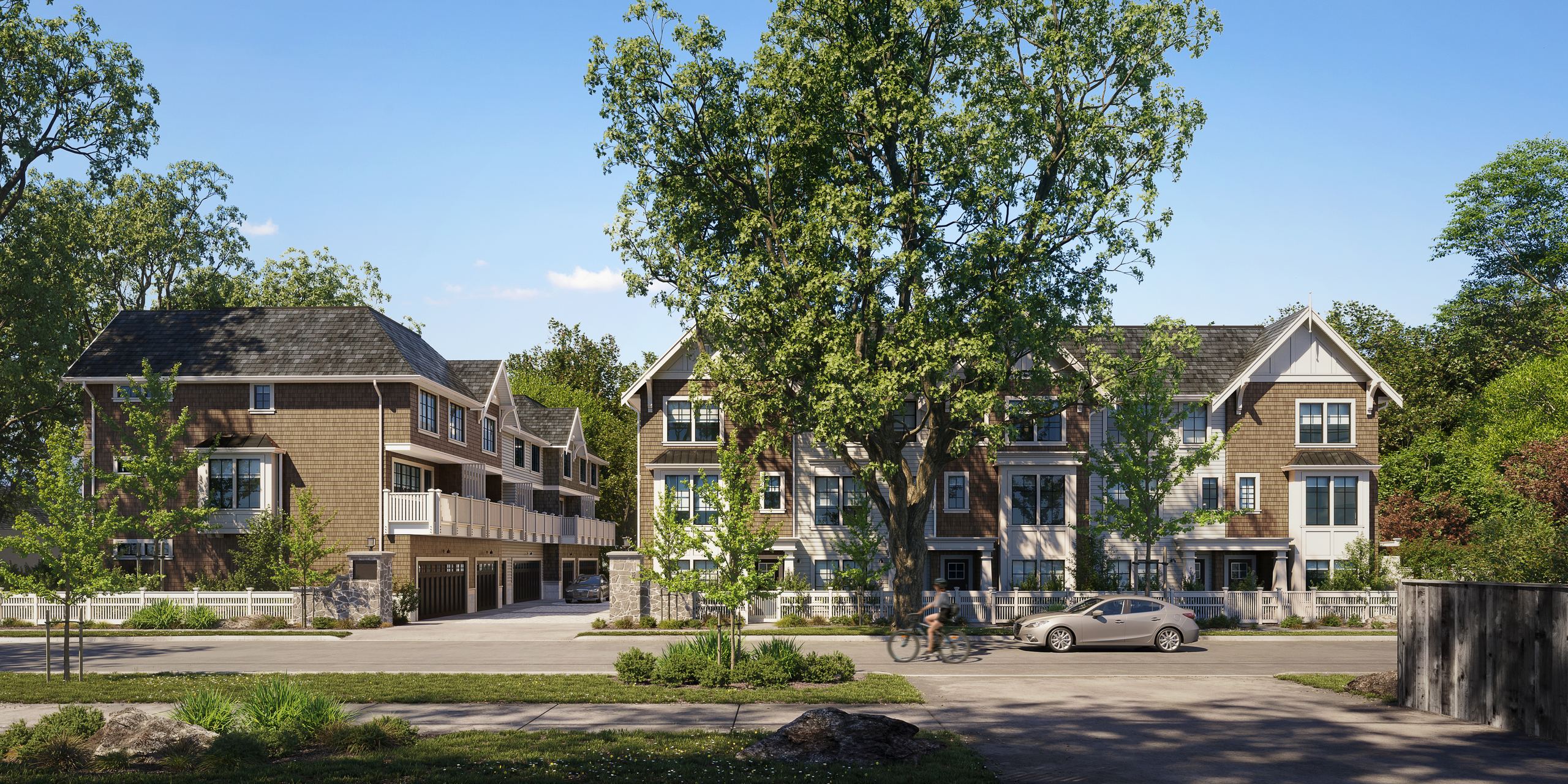 The townhomes in full daylight with a cyclist and cars on the street
