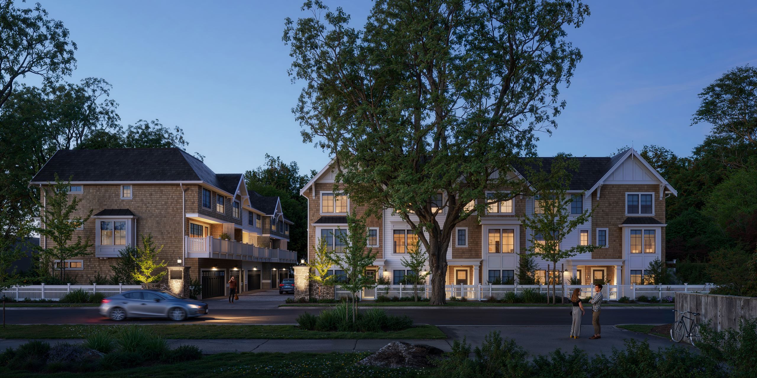 The townhomes at dusk with warm window light and neighbours talking on the sidewalk